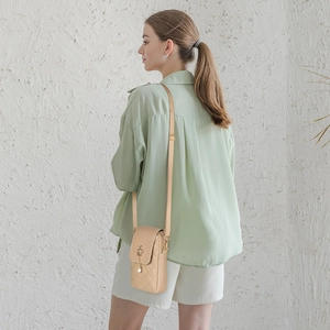 Elegant beige quilted crossbody phone bag with pearl crown charm on light green shirt