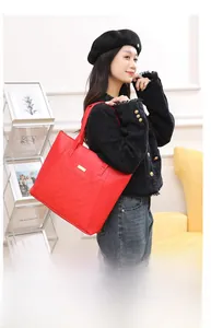 Detail of red quilted tote bag featuring a metallic logo plate and large capacity