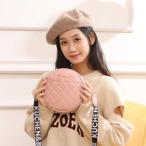 Pink round quilted crossbody bag with stylish letter strap shown with model