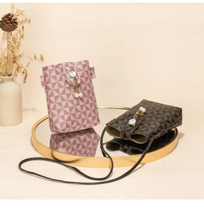 Detail of printed crossbody phone bags with pearl cat charms on a mirror tray