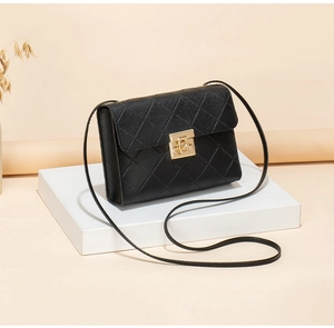 Detail of black quilted crossbody bag featuring a golden square lock and cross-grain texture