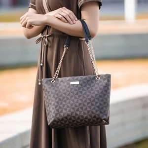 Sac cabas marron à motif géométrique avec anses en chaîne dorée porté par un mannequin