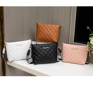 Detail view of quilted bucket bags in brown, white, black, and pink with canvas straps