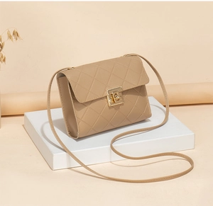 Detailed view of beige crossbody bag with quilted texture and golden twist lock