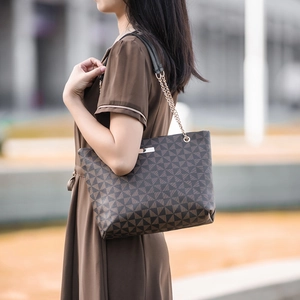 Sac cabas marron à motifs géométriques avec chaîne dorée porté par un mannequin