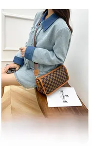 Detail of brown checkered crossbody bag with wide shoulder strap and gold hardware