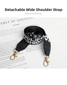 Detail of detachable wide woven shoulder strap with black letter print and gold clasps