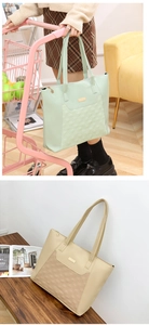 Detail of quilted tote bag with golden metal plaque and floral zipper puller