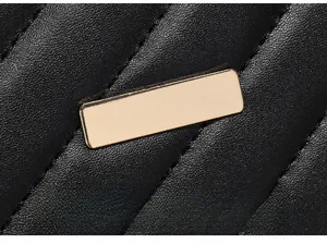 Close-up of black quilted leather camera bag with gold rectangular metal detail