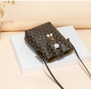 Detail of crossbody mini bag featuring geometric prints and gold-tone cat pearl charm