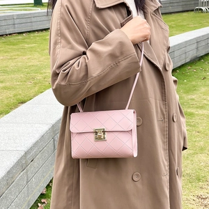 Pink quilted crossbody bag for women featuring a gold turn-lock closure on outdoor lawn