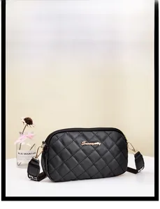 Detail of black quilted crossbody bag with golden logo and embroidered wide strap