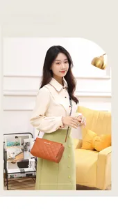 Close-up of quilted tan crossbody bag with gold logo and elegant double zipper design