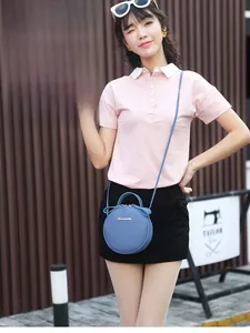 Blue lychee leather round handbag featuring a top handle and gold logo in outdoor setting
