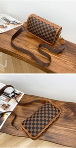 Detail of cylindrical crossbody bag with brown checkerboard pattern and nylon strap