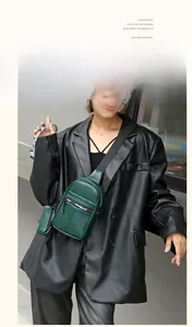 Details einer dunkelgrünen Brusttasche aus Leder mit breitem Gurt und kleiner Geldbörse