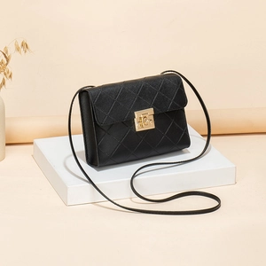 Classic black quilted crossbody bag with golden twist-lock on white geometric pedestal