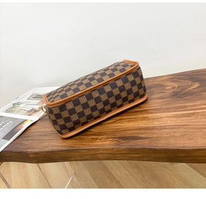 Close-up of the checkered pattern and brown leather trim on a stylish crossbody bag