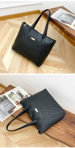 Detail of black quilted tote bag with golden metal plaque and floral zipper pull