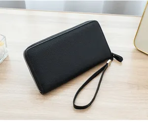 Close-up of black lychee grain long wallet with silver zipper on a wooden table