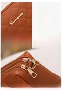 Detail of brown quilted PU leather handbag featuring dual gold zippers and metal logo