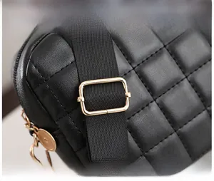 Detail of black quilted camera bag with adjustable strap and gold-tone metal buckle