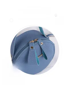 Detail of light blue lychee pattern round bag featuring double metal zippers and gold studs