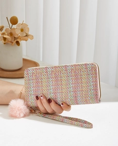 Détail du portefeuille en tweed tissé avec pendentif pompon rose et zip doré