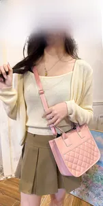 Detail view of pink quilted PU leather handbag with adjustable strap and top handles