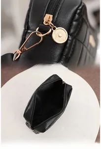 Detail of black quilted crossbody bag showing golden zipper and spacious inner compartment
