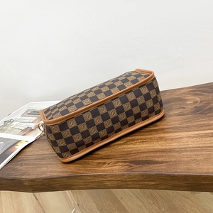 Elegant brown checkered shoulder bag with letter S logo on a vintage wooden table
