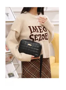 Detail of black quilted leather crossbody bag with elegant gold metal hardware decoration