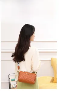 Lifestyle view of a small orange quilted crossbody bag worn by a model in casual setting