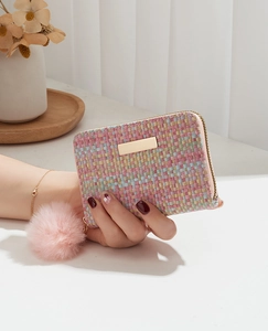 Close-up of woven mini card purse with pink pom-pom and gold zipper detail