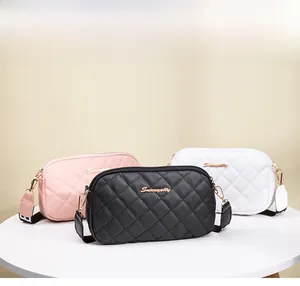 Detailed view of quilted camera bags in pink, black, and white with gold hardware