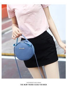 Detail of light blue round crossbody bag with lychee texture and bow decoration
