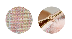 Macro detail of multi-color woven fabric card bag with pink fur pompom and gold zipper