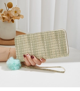 Détail d'un long portefeuille tissé vert avec pompon en peluche et dragonne amovible