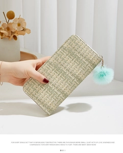 Détail du portefeuille tressé à carreaux vert et beige avec un pompon en peluche doux