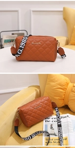 Detail of brown quilted crossbody bag with golden logo and embroidered wide strap