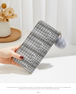 Détail du portefeuille tressé avec fermeture dorée et breloque boule en peluche grise