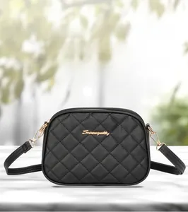 Vue macro du sac caméra en cuir noir matelassé avec logo doré et détail de double fermeture