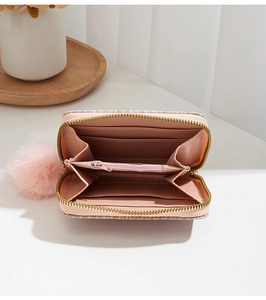 Detail of light pink woven wallet showing multi-slot accordion interior and pompom charm