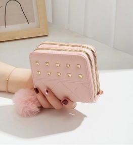 Vue détaillée du mini portefeuille rose avec double fermeture éclair, clous et pompon