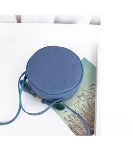 Detail of navy blue round crossbody bag with litchi grain texture and top zipper