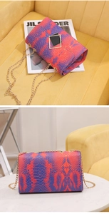 Detail of red and blue snakeskin texture on a luxury crossbody bag with gold chain