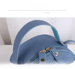 Close-up of blue lychee grain leather handbag with gold rivets and double zippers