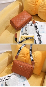 Detail of brown quilted crossbody bag with metal logo and patterned wide strap
