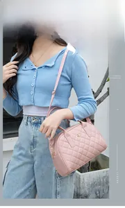 Dettaglio della borsa rosa trapuntata con logo floreale dorato indossata da una modella