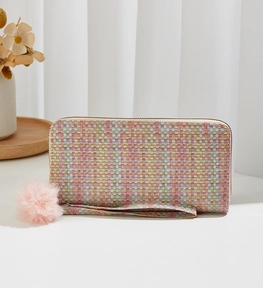 Gros plan du sac tissé à carreaux avec pompon rose et dragonne sur fond blanc pur